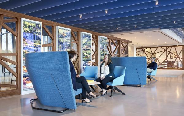 Trinity Gate Investments interview with Acousti Engineering, people chatting on blue sofas under an acoustic celling